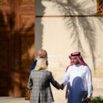 Wide shot of a professional woman greeting a Saudi business man in a partnership meeting outdoors near an office building